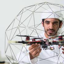 Arab male student from Khalifa University studies Quadprop drone that he built for robotics classes.