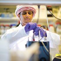 An Arab student with latex gloves working in the lab with industrial chemicals and tools