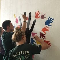 Volunteers paint hands onto their wall mural at a public hospital