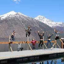 group of people jumping for joy on dock at Lake MacDonald in Glacier National Park in Montana