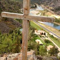 wooden cross at the top of a mountain overlooking a valley with Camp Bighorn below