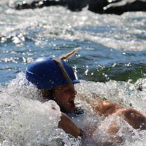 girl with helmet swimming in rapids during water rescue school