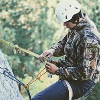 guy rock climbing and inspecting gear on ropes