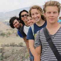 five people standing in a row in front of pyramids in central Mexico