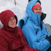 two guys in winter coats sitting in snow