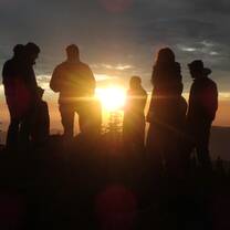 group of people standing in a circle at sunset
