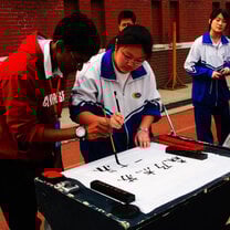 student from high school language program learning chinese calligraphy instructed by chinese teens
