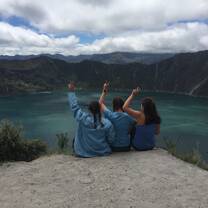 Three girls sit on the edge of a crater within a volcano 