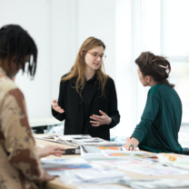 Student talking to a tutor in front of a table of materials
