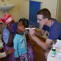 Volunteer examining a children on the hands-on medical clinic program