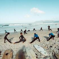 Group os youngsters warm up on the beach before going in the water