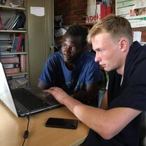 Merlin helping out Vincent with some computer training, 'the internet has only really reached our community in January 2019, when they built a cell phone tower for us.'