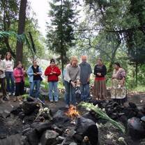 a fire burns outside on a group of large boulders while a group watches the fire