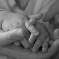 Teenage mother holds baby's hand