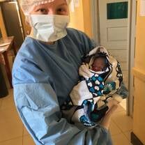 (image of me in surgical gear holding newborn I'd just helped deliver)