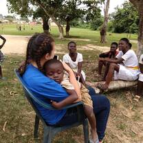 A young Kenyan child child sleeps in the arms of a female Village Book Builders volunteer.