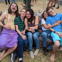 A group of friends laughing and sitting on a bench at a party.