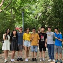 A group of friends in a park, smiling at the camera. 