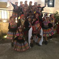 A diverse group of volunteers and locals wearing bright traditional Peruvian carnival clothes.