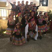 A diverse group of volunteers and locals wearing bright traditional Peruvian carnival clothes.