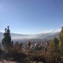 The Cusco landscape in the morning - fog over the city surrounded by greenery and mountains.