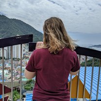 picture of a girl looking out over a crowded colorful village and the sea