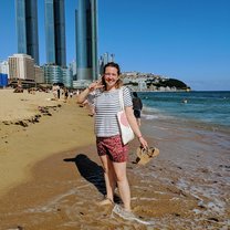 girl standing on a beach with buldings in the background