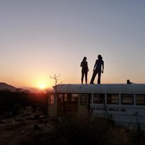 Two figures standing on top of a bus