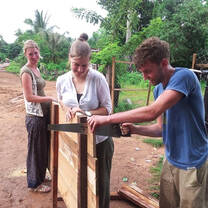 Volunteers cutting wood for rural construction 