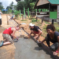 Volunteers putting cement on sand floor