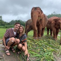 A young man and woman sitting in front of a group of elephants
