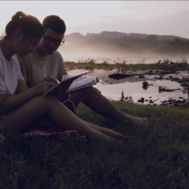 Two students studying together by a river
