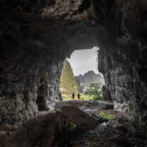 Exploring caves when not studying is a great past time in Yangshuo Two figures sillouetted in a cave opening