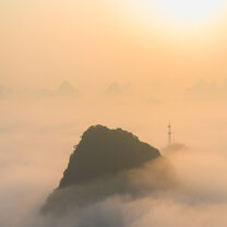 A magical day on Tv Tower in Yangshuo A cloud inversion and orange cloud below a rising sun