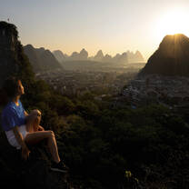 A girl sits watching the sunrise in Yangshuo