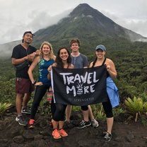 Standing in front of the Arenal volcano with the four other volunteers I lived with on a weekend adventure. We are holding a flag from the company Serengetee, that reads "Travel More."