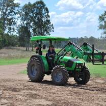 Participant learning to drive a green tractor across the paddock