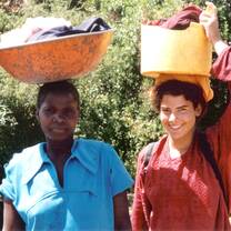 Participant and African woman carry baskets of clothes on their heads