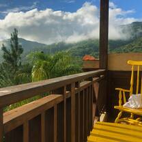 View of green mountains covered in clouds from balcony. 