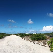 blue sky with fluffy clouds and a single white road 