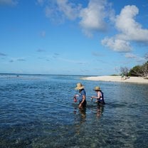 two people wade through  ocean water 