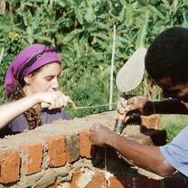 Participant works with local craftsman building a brick wall