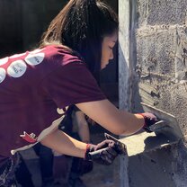 One of my Rustic Pathways group members plastering walls with cement.