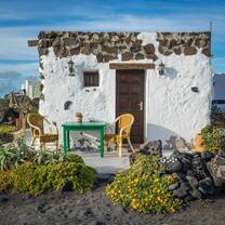 A quaint white stone house with green furniture surrounded by lush plants on a sunny day, showcasing the natural beauty and slow-paced lifestyle that RVF International participants can enjoy while exploring Spain.