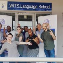 Group of teachers standing in front of a Wits Language School sign