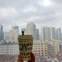 Overlooking buildings in Huangpu Holding a Starbucks cup in front of a window on the high floor of a building, overlooking Huangpu
