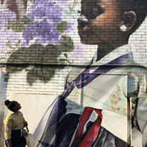 Girl looking at large wall mural of young girl in traditional Korean dress (hanbok)
