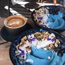 A beautifully done smoothie bowl with a cup of coffee.