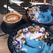 A beautifully done smoothie bowl with a cup of coffee.