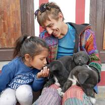A traveler holding puppies next to a young girl.